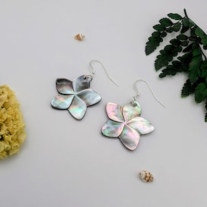 Peut inclure: Une paire de boucles d'oreilles argentées avec des pendentifs en forme de fleur noire irisée. Les fleurs ont un reflet irisé multicolore.