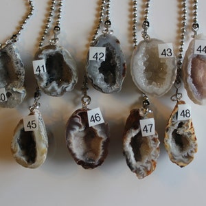 May include: Eight agate geode pendants with silver chains. The geodes are various shades of brown, white, and gray. The pendants are numbered 40 through 48.