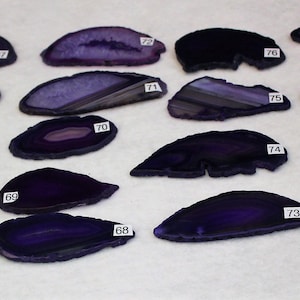 May include: A collection of 14 purple agate slices, each with unique patterns and textures. The slices are numbered 63 through 79.