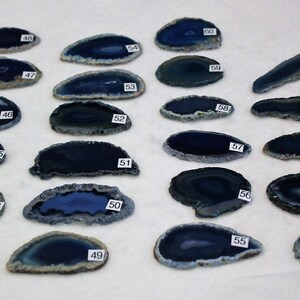May include: Assortment of 20 blue agate slices, each with a unique pattern and shape. The slices are arranged in rows on a white surface.