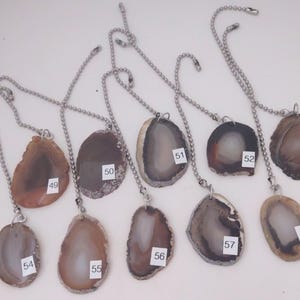 May include: Ten agate slices on silver chains, each slice is a different color and pattern. The slices are numbered 49 through 58.