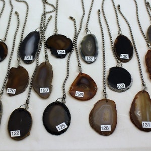 May include: Assortment of 18 agate pendant light pulls with silver chains. The agates are in various shades of brown, black, and white.