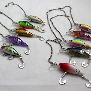 May include: A collection of ten colorful fishing lures with silver hooks and attached ball chains. Each lure is numbered from 1 to 10. The lures feature various color schemes, including green, red, purple, and gold.