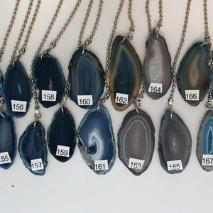 May include: Twenty agate slice pendants on silver chains. The agate slices are various shades of blue and gray with white and brown banding. The pendants are numbered 150 to 170.