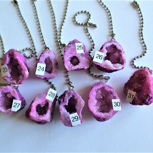 May include: Nine pink crystal geodes with numbers 23-31 on them, attached to silver chains. These crystals are perfect for adding a touch of nature to your home decor.