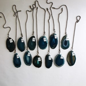 May include: Twelve agate pendant light pulls with silver chains. The agates are various shades of blue and green with white markings. The pendants are numbered 13 through 24.