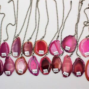 May include: Twenty agate slices on silver chains with numbers 162 through 181. The agate slices are various shades of pink, red, and orange.