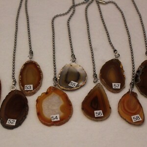 May include: Ten agate slice pendants on silver chains. The agate slices are in various shades of brown, orange, and gray. The pendants are numbered 50 through 61.
