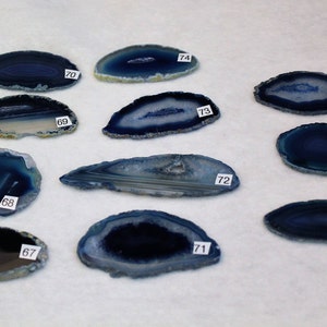 May include: Ten blue agate slices with white and gray banding. Each slice is numbered 67 through 77.