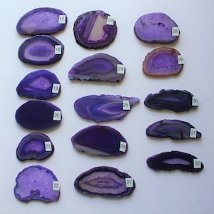 May include: A collection of 16 purple agate slices, each with unique patterns and textures. The slices are numbered 17 through 32.
