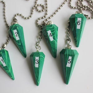 May include: Six green and silver pendulums with numbers 1 through 6 on them.
