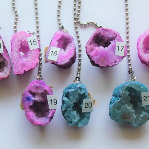 May include: Seven pink and two blue crystal geodes on silver chains. The geodes are numbered 14 through 21.