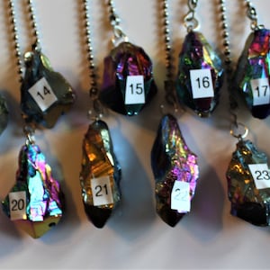May include: A collection of 11 iridescent rainbow crystal pendants with silver chains. Each pendant is numbered from 13 to 24.