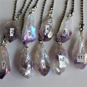 May include: Twelve iridescent amethyst crystal pendants with silver chains. Each pendant is numbered 1 through 12.