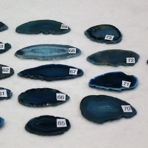 May include: A collection of 15 blue agate slices, each with a unique pattern and shape. The slices are numbered 60 through 75.