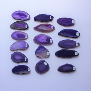 May include: Sixteen purple agate slices with white banding, numbered 1 through 16. The agate slices are arranged in two rows of eight, with the numbers visible on the right side of each slice.