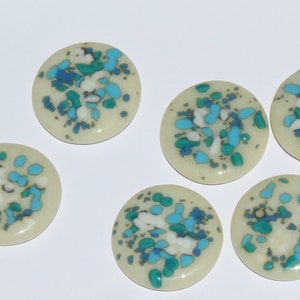 May include: Six round, cream-colored ceramic tiles with a speckled pattern of blue, green, and white.