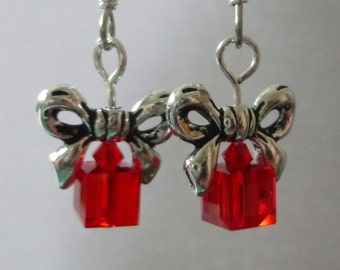 Red earrings that look like gift wrapped packages with silver bows