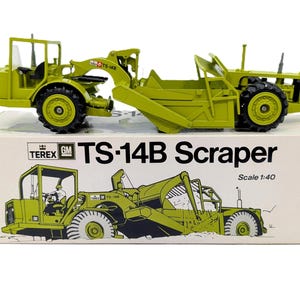 May include: A lime green Terex TS-14B scraper scale model vehicle with black tires and an open operator cab. The model sits atop its original white cardboard box, which features a printed illustration of the machine and the text TS-14B Scraper.