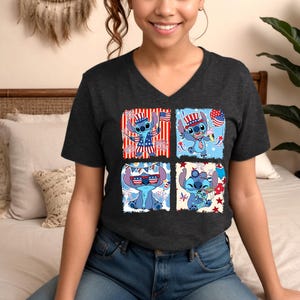 Puede incluir: Camiseta gris oscuro con cuello en V con un dise&ntilde;o de cuatro paneles de un personaje de dibujos animados azul con atuendo patri&oacute;tico. Cada panel muestra al personaje con elementos de la bandera estadounidense, fuegos artificiales y conos de helado.