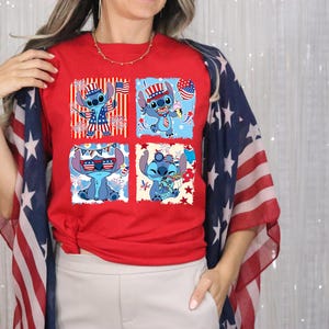 Puede incluir: Camiseta roja con un dise&ntilde;o de cuatro paneles de un personaje de dibujos animados azul con atuendo patri&oacute;tico. El personaje se representa con una bandera estadounidense, fuegos artificiales y accesorios festivos. La persona lleva un chal con la bandera estadounidense.