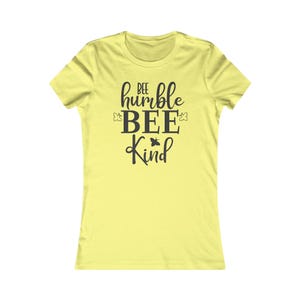 May include: A yellow women's t-shirt with the text "bee humble bee kind" in black lettering. The text is stylized with a bee graphic.