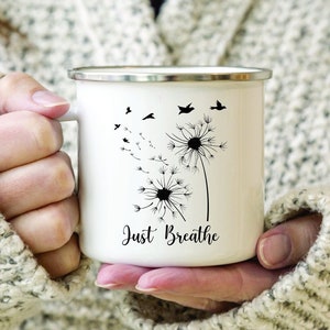 Pode incluir: Caneca de esmalte branco com um desenho de dente-de-leão preto e o texto "Just Breathe".