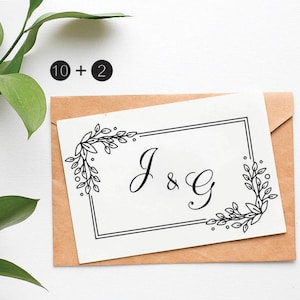 Puede incluir: Una tarjeta blanca con un borde negro y un diseño floral. Las iniciales "J & G" están escritas en cursiva dentro del marco.