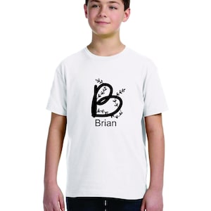 Pode incluir: Camiseta branca com uma letra B estilizada preta com folhas ao redor e o nome Brian impresso abaixo.
