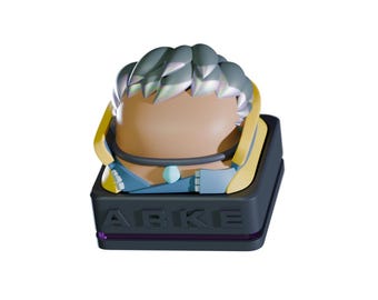 May include: A stylized figurine with a light brown face, silver hair, and blue and yellow accents. The figurine is set on a dark gray base with the word "ARKE" in white lettering. A small purple dot is visible.