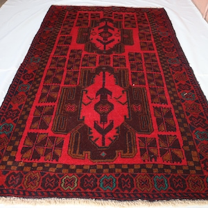 May include: A red rug with a dark brown geometric pattern. The rug has a fringe border.
