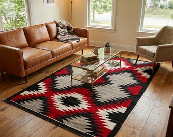 May include: A rectangular area rug featuring a geometric pattern in red, black, white, and gray. The rug is positioned on a wooden floor in a room with a leather sofa, a glass-topped coffee table, and an upholstered armchair nearby.