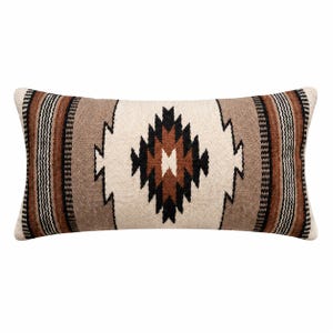 Peut inclure: Un coussin rectangulaire présentant une texture tissée avec un motif central en losange dans des tons crème, beige, marron et noir. Le design comprend des bordures rayées verticales des deux côtés, créant un motif symétrique sur la surface.