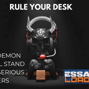 May include: A black demon skull headset stand with red accents, holding a black game controller. The stand has a gold-colored base and the text "RULE YOUR DESK" and "THE DEMON SKULL STAND FOR SERIOUS GAMERS". The Essay On Loadout logo is in the bottom right.