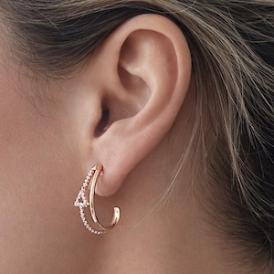 May include: A white ceramic mug with a black handle and the text "But First, Coffee" in a bold, black font. The mug is set against a blurred background. The mug appears to be approximately 10 cm tall.