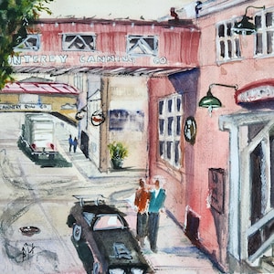 Puede incluir: Una pintura de acuarela de una escena callejera en Monterey, California. La pintura representa un edificio con el texto "Monterey Canning Co." y "Cannery Row Co.". El edificio está pintado en tonos de rojo, marrón y blanco. Hay un coche negro aparcado en la calle y dos personas caminando en la distancia.