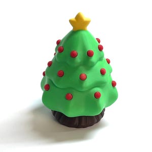 Könnte beinhalten: Grüne Weihnachtsbaumfigur mit roten Kugeln und einem gelben Stern. Der Baum hat einen braunen Sockel und steht vor einem weißen Hintergrund. Eine festliche Dekoration für die Weihnachtszeit.