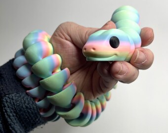 May include: A rainbow-colored, flexible, snake-shaped toy with a black eye. The toy is made of a soft, pliable material and is designed to be stretched and bent.