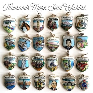 May include: A collection of 20 enamel and silver charm pendants featuring various locations and landmarks. The charms are shaped like shields and have colorful enamel designs. Some of the locations include Clearwater, Florida, Louisville, Kentucky, Firenze, Italy, Cape Cod, Massachusetts, Virginia Beach, Virginia, Alaska, Honolulu, Hawaii, South Dakota, Yellowstone Park, Saratoga Springs, New York, Disneyland, United Nations, Boothbay Harbor, Maine, Puerto Rico, New York City, Barbados, President John F. Kennedy, and Brazil.