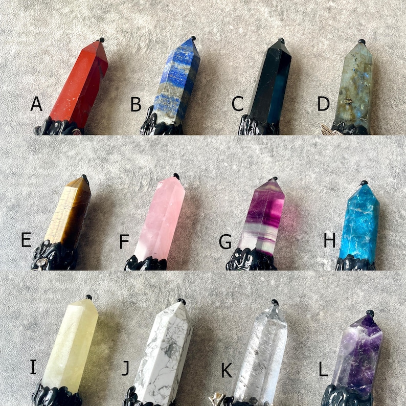 May include: Twelve different crystal point pendants with black metal bases. The crystals are in various colors, including red, blue, black, grey, brown, pink, purple, teal, white, and amethyst.