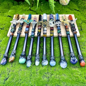 May include: Twelve black wands with different colored crystal tips and decorative metal accents. Each wand is adorned with various gemstones and crystals.