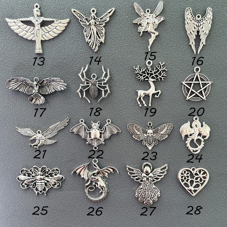 K&ouml;nnte beinhalten: Eine Sammlung von silberfarbenen Metallanh&auml;ngern, jeweils mit einem einzigartigen Design. Die Anh&auml;nger zeigen gefl&uuml;gelte Figuren, Tiere und Symbole, wie eine Spinne, eine Fledermaus und ein Pentagramm. Die Nummern 13-28 sind sichtbar.