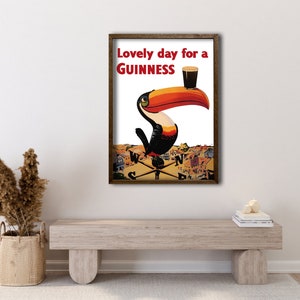 May include: A framed vintage poster with a toucan holding a glass of Guinness. The poster reads "Lovely day for a GUINNESS".