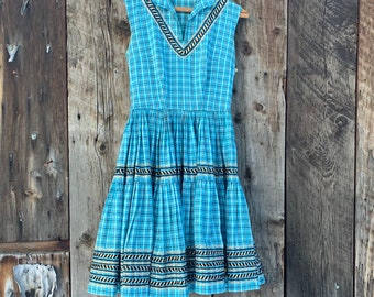 Impresionante y raro vestido de patio vintage de los años 50 a cuadros turquesa con falda muy amplia y ribete de zigzag negro y metalizado. Talla pequeña.