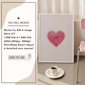 Puede incluir: Un marco blanco con un dise&ntilde;o de coraz&oacute;n de huella digital roja en su interior. El marco est&aacute; sobre una superficie marr&oacute;n claro con una taza de caf&eacute; blanca y un platillo blanco.