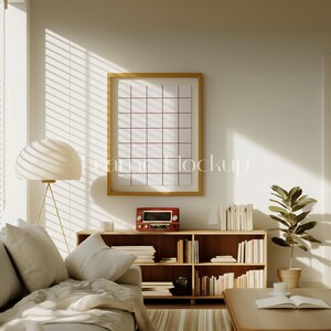 Pode incluir: Um interior de sala de estar com um sof&aacute; branco, uma estante de livros de madeira cheia de livros, um p&ocirc;ster emoldurado, uma l&acirc;mpada e uma planta em vaso.