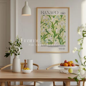 May include: A framed print with a floral design featuring white flowers and green leaves. The print is titled "HANACO" and is displayed on a white wall in a dining room setting.