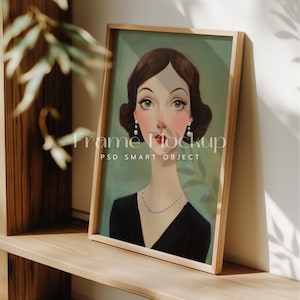 以下が含まれることがあります： 茶色の髪と黒いドレスを着た女性の絵画が額装されています。背景は薄い緑色です。絵画は木製の額縁に入っています。