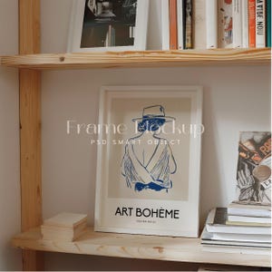 May include: A white framed poster with a drawing of a person wearing a hat and a white dress. The poster has the text "ART BOHEME" and "POSTER NO. 01" on it.