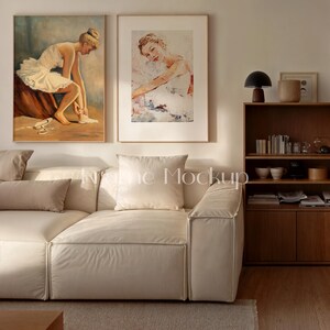 May include: Two framed art prints of ballerinas hang above a cream-colored sofa. The artwork features a ballerina in a white tutu, with one print showing her seated and the other in a more abstract pose. The room has a modern, minimalist aesthetic.
